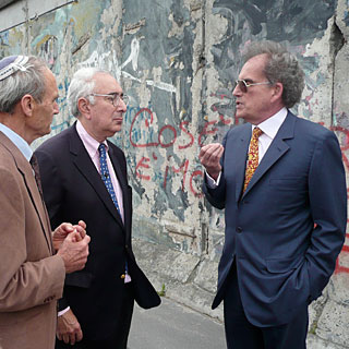 David Berlinski (r) discusses the implications of eugenics and evolution with Gerald Schroeder (l) and Ben Stein in front of the Berlin Wall.